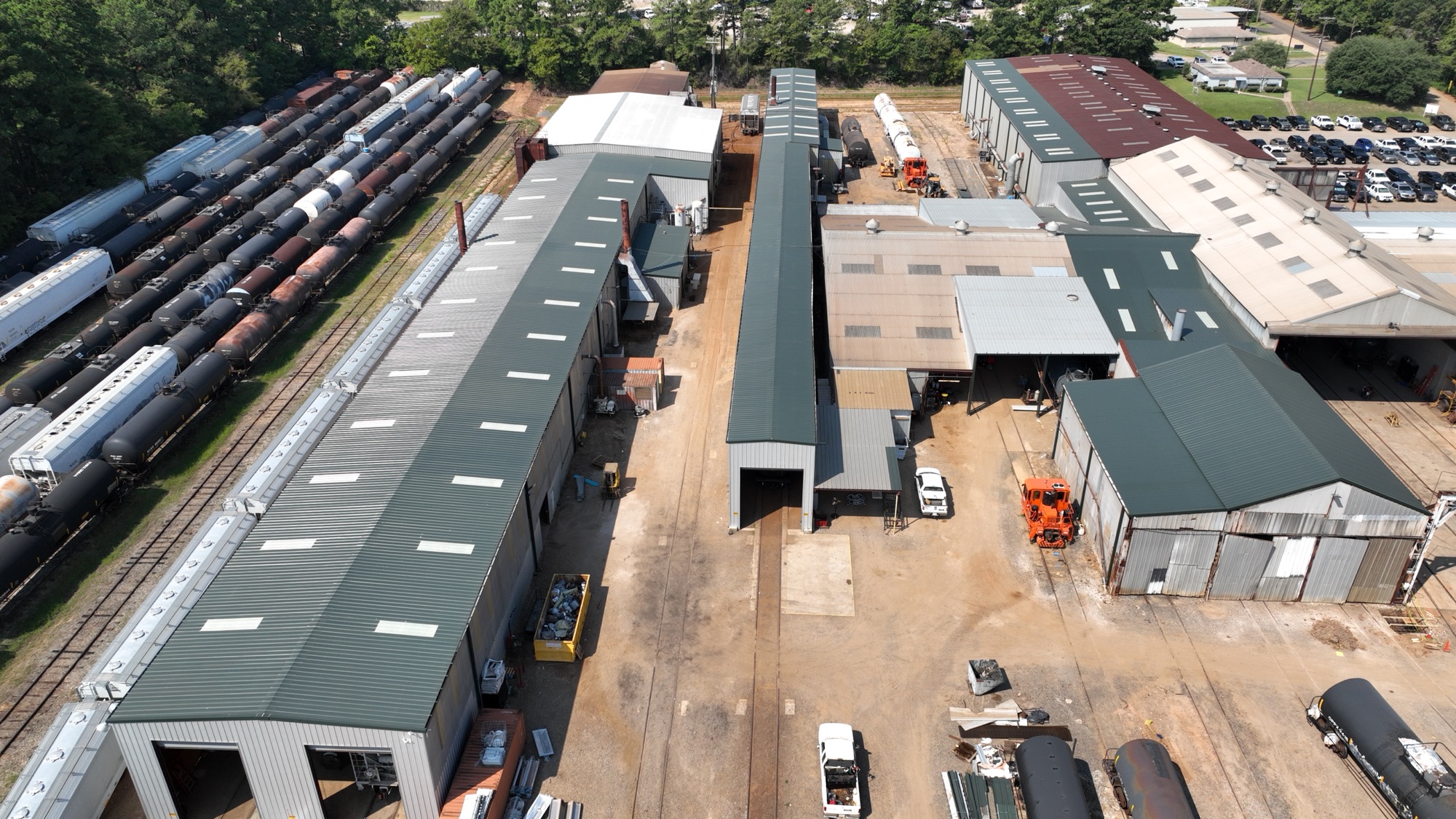 Bayou Roofing standing-seam metal re-roof on Eagle Railcar Services repair facility in Louisiana — aerial view of completed teal metal roofing across multiple industrial buildings with rail cars on adjacent tracks